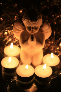 A praying angel surrounded by burning votive lights